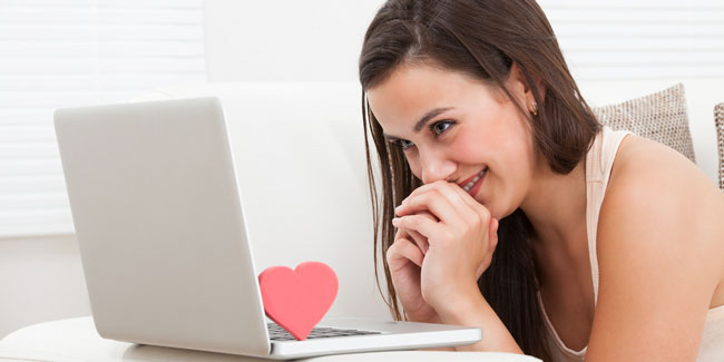 Side view of beautiful young woman dating online on laptop